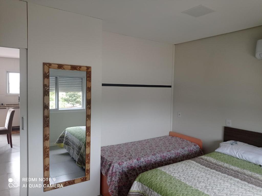 a bedroom with two beds and a mirror at Apartamento FLAT no centro - Passo de Torres SC in Pirataba
