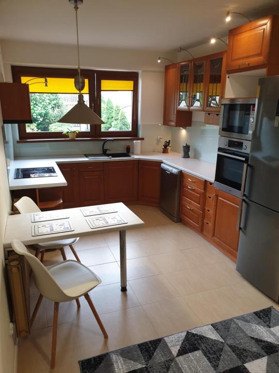uma cozinha com armários de madeira, uma mesa e um frigorífico em Apartament pod Grojcem em Żywiec