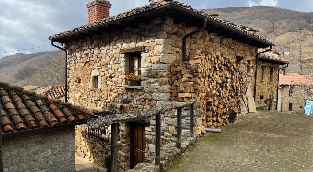 une ancienne maison en pierre avec un tas de bois dans l'établissement Elpajardeportilla, à León