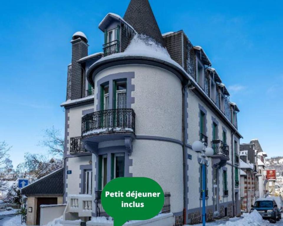 a large white building with a balcony on a street at La Tour Pom'Pin in La Bourboule