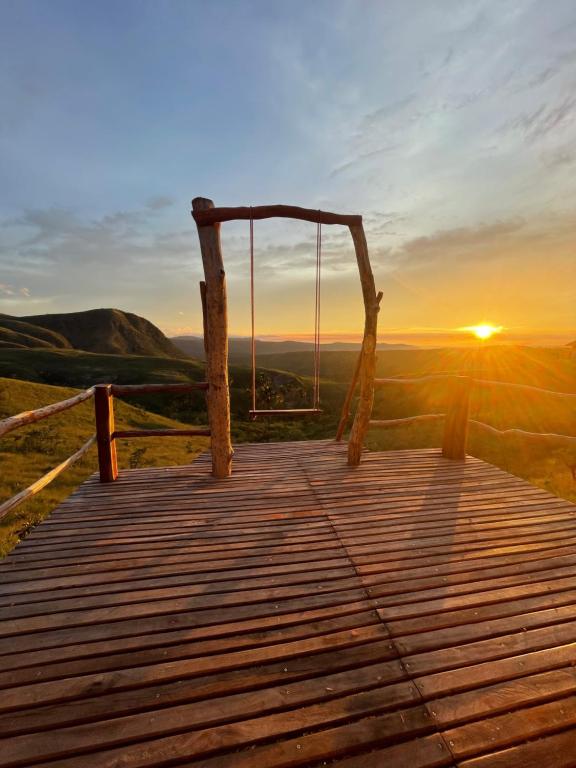 a swing on a wooden bridge with the sunset in the background at Chalé Beija Flor, venha viver essa experiência!! in Sao Jorge
