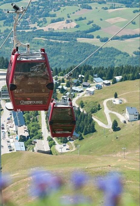 two red cable cars going up a mountain at Charmant T2 proche des pistes superbe vue in Chamrousse