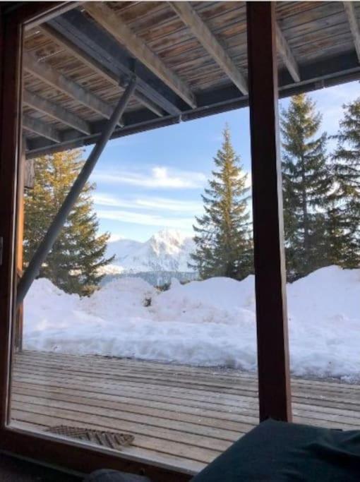 a view of a snow covered mountain through a window at Charmant T2 proche des pistes superbe vue in Chamrousse