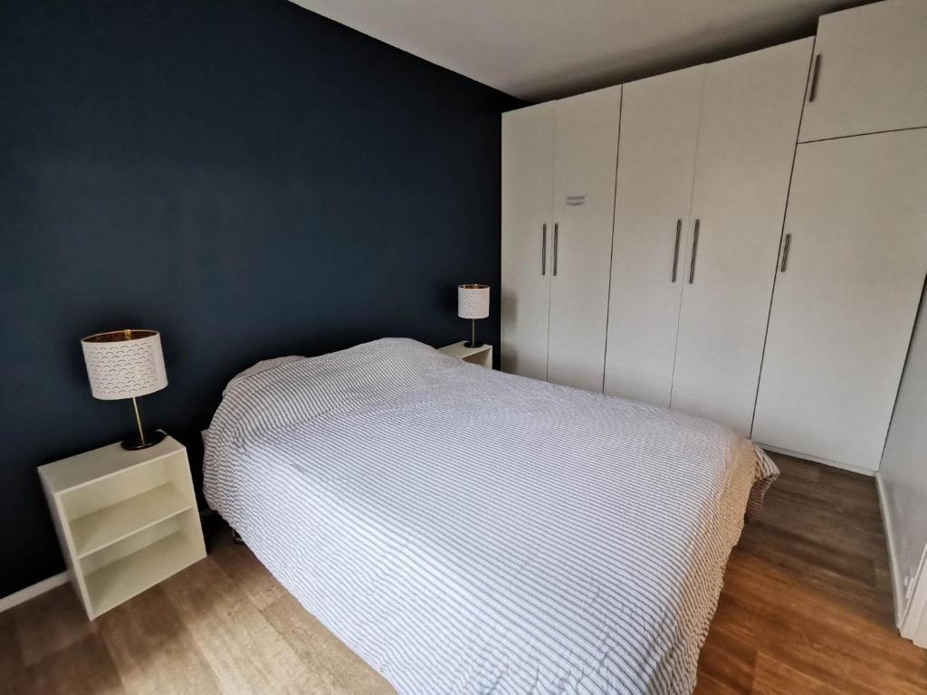 a bedroom with a white bed and a blue wall at Appartement Noisiel 77 (proche Disneyland & Paris) in Noisiel