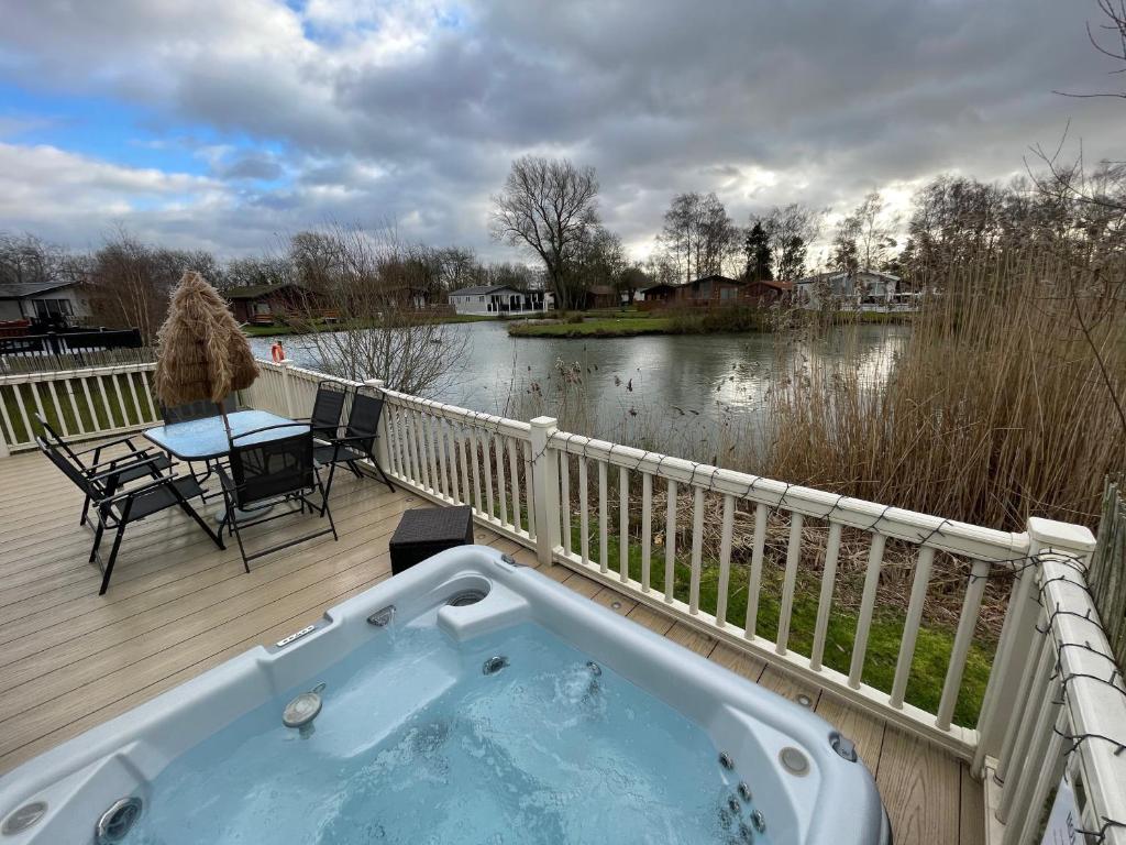 a jacuzzi tub on a deck next to a lake at Luxury Lakeside Lodge L2 with Hot tub situated at Tattershall Lakes Country Park in Tattershall