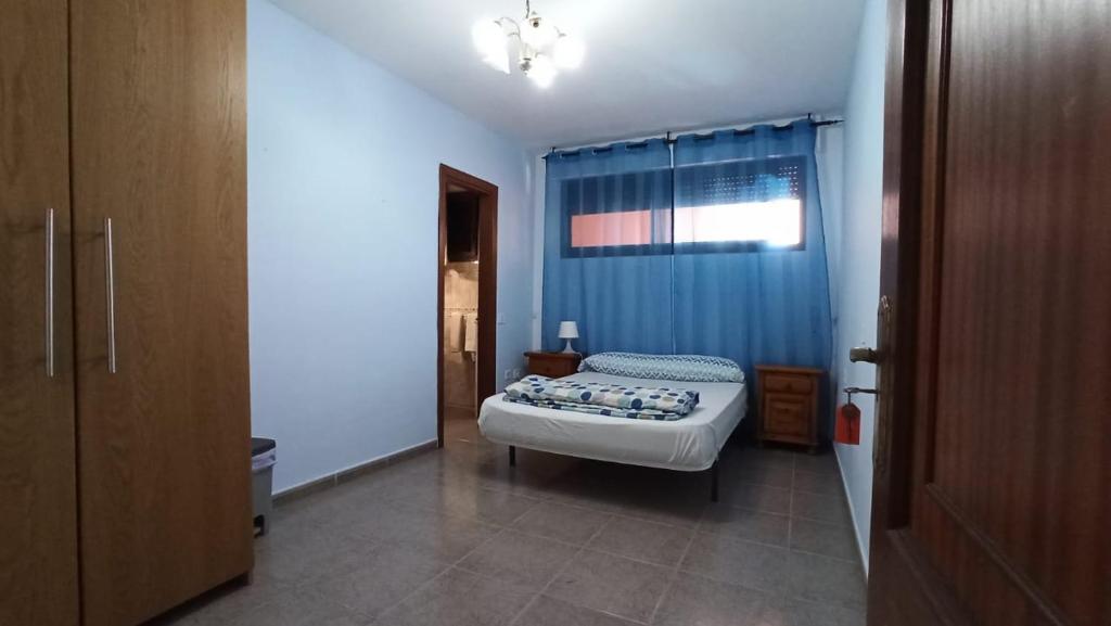 a bedroom with a bed and a blue curtain at Los Cristianos centro, room with a private bathroom in shared apartment in Arona