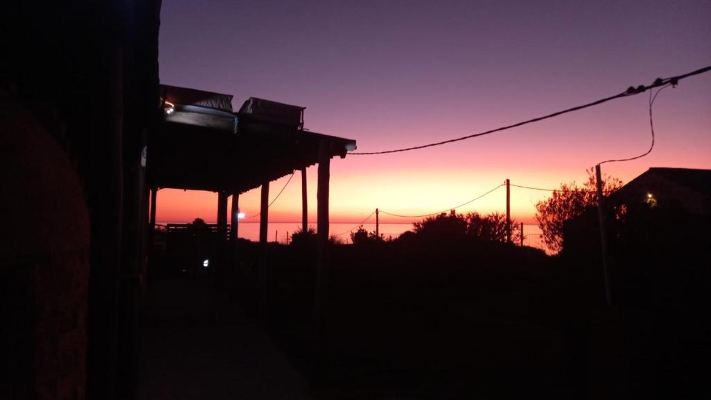 un coucher de soleil dans le ciel avec un bâtiment au premier plan dans l'établissement Agua Corazones, à San Luis