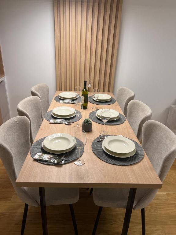 uma mesa de madeira com cadeiras e pratos e copos de vinho em apartman Lara em Jahorina
