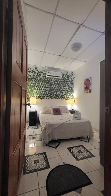 a bedroom with a bed and a wall with plants at Casa Luz Mi casa tu casa in Sabanitas