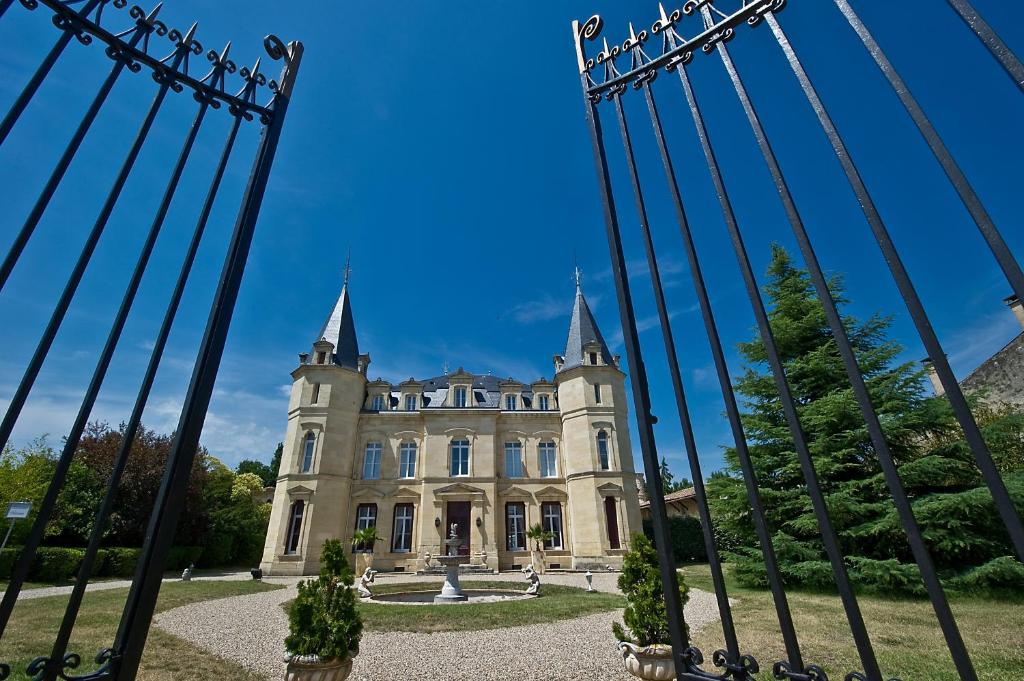an old castle seen through the gates of a fence at Chateau Pontet d'Eyrans & Spa in Eyrans-de Soudiac