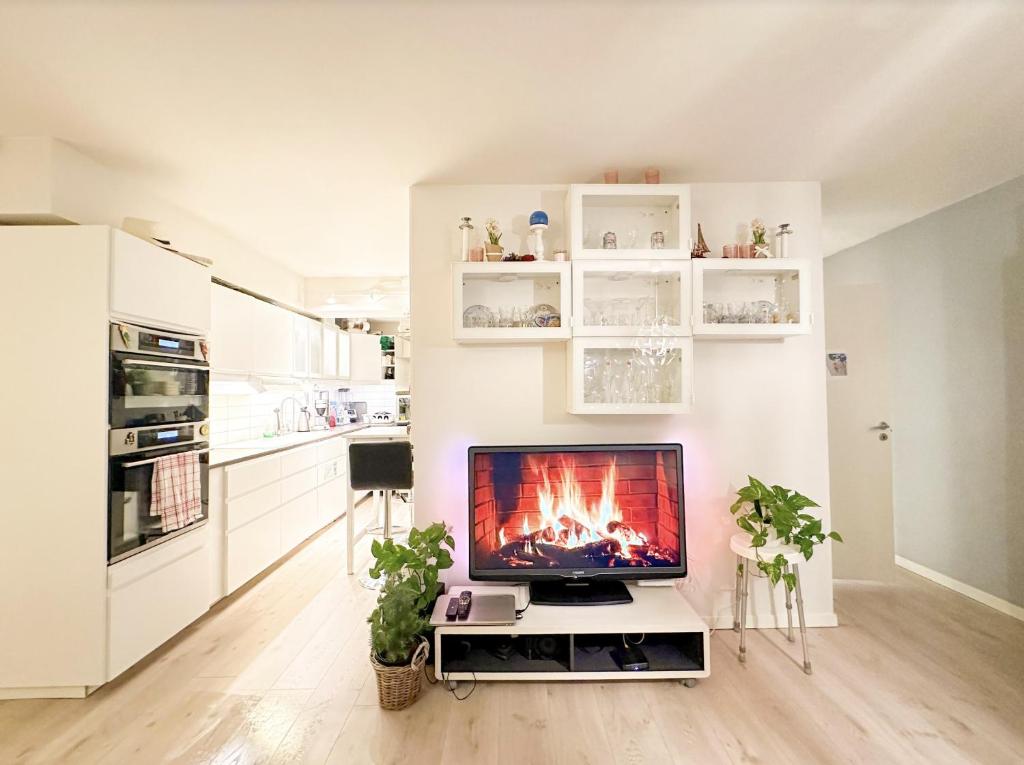 ein Wohnzimmer mit einem TV auf einem Stand mit einem Kamin in der Unterkunft Central and cozy next to Oslo S in Oslo