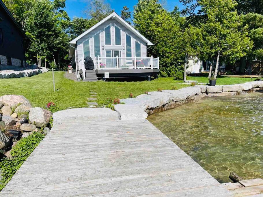 a house with a boardwalk leading to a body of water at SouthLake Cottage on The Lake. in Washago