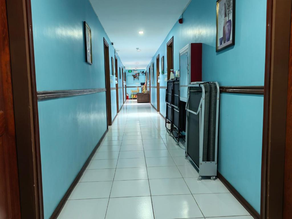 un couloir d'un hôpital avec des murs bleus et du carrelage blanc dans l'établissement YellowPad Hotel (SM-Eco), à Davao