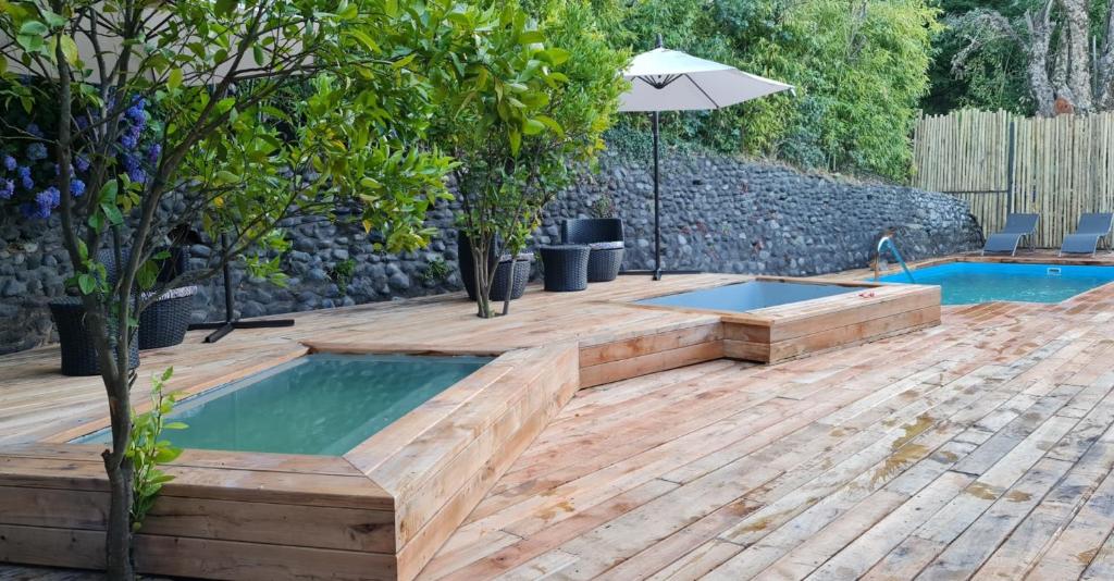 a pool with a wooden deck and a swimming pool with an umbrella at Borde Luz Hotel Boutique in Pucón