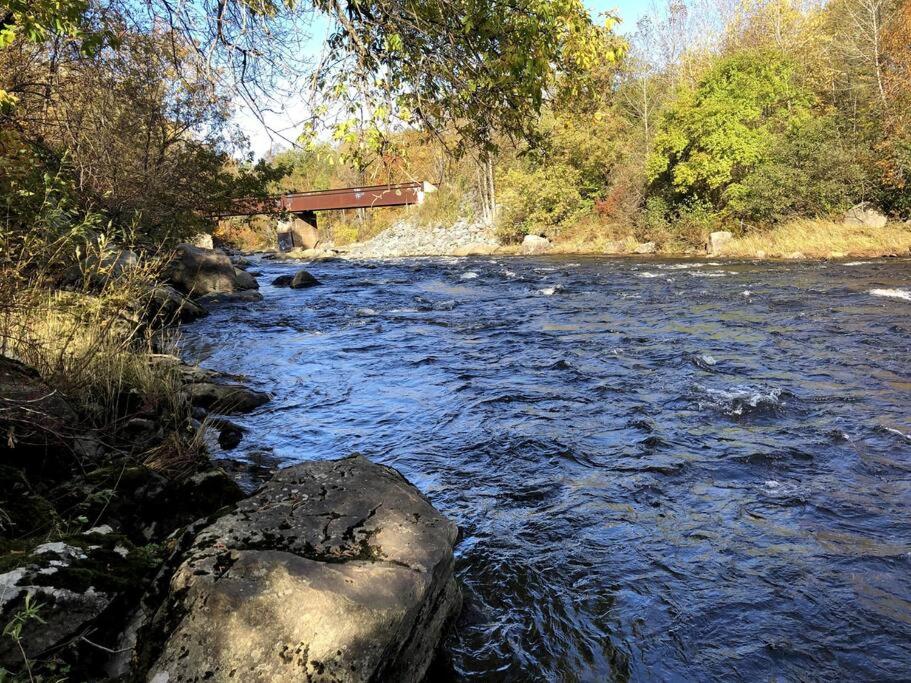 Un río con un puente y un poco de agua y rocas en La cachette de la rivière au saumon et spa, en Scotstown