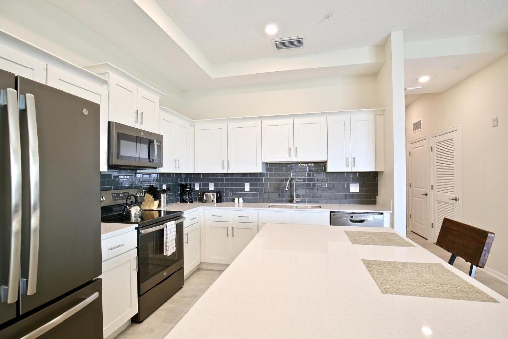 a kitchen with white cabinets and a black refrigerator at 10 min to Disney! Amazing location in Kissimmee