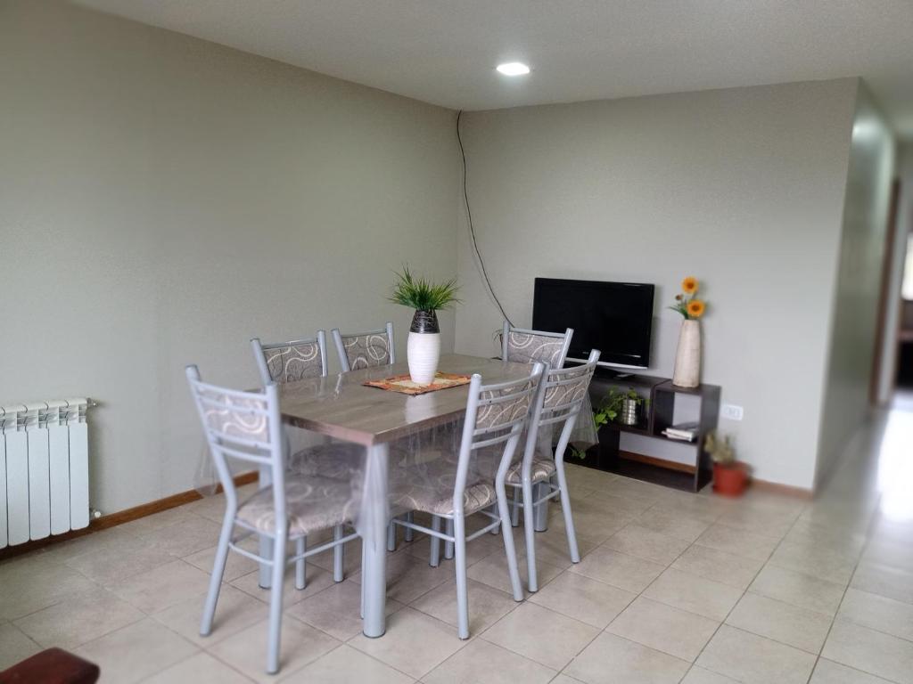 una sala da pranzo con tavolo, sedie e TV di Calido alojamiento a Ushuaia