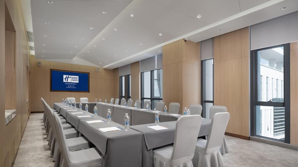 une salle de conférence avec une grande table et des chaises blanches dans l'établissement Holiday Inn Express Shunde Daliang, an IHG Hotel, à Shunde