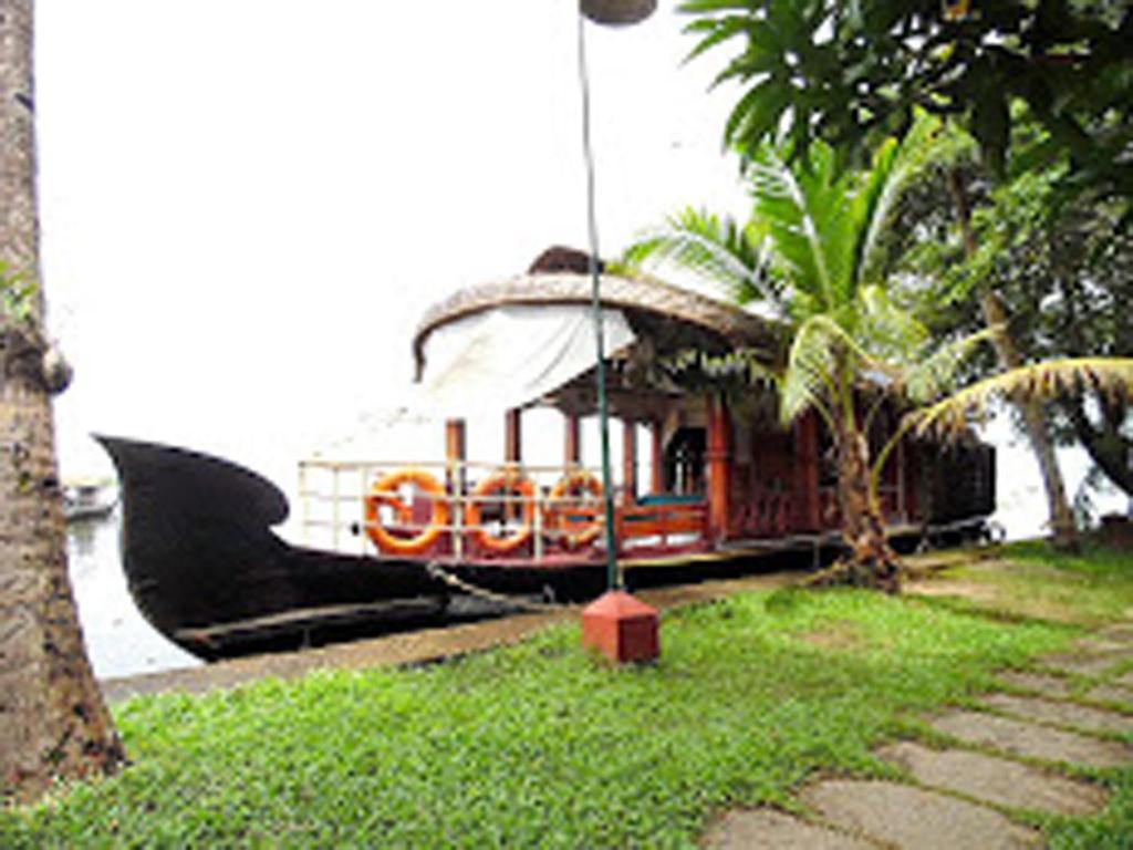 a boat in the water next to a house at Houseboat cruise in the backwaters of Kerala. in Kottayam