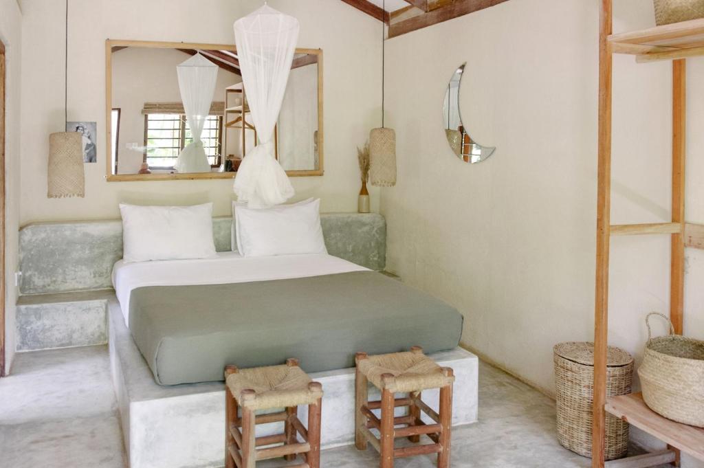 a bedroom with a bed with two chairs and a mirror at The Kip in Ahangama