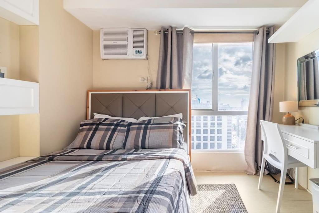 a bedroom with a bed and a desk and a window at 20t7 floor Cebu IT Park studio walking distance to everything in Cebu City