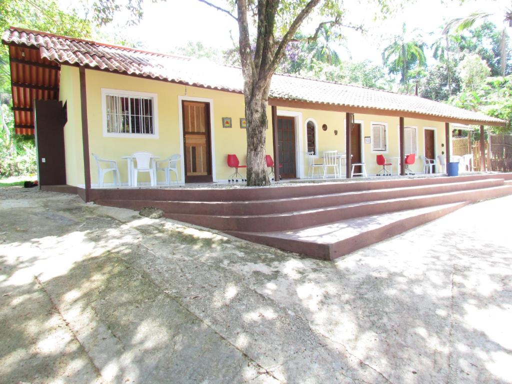 a house with tables and chairs in front of it at Chalés Damata in Ubatuba