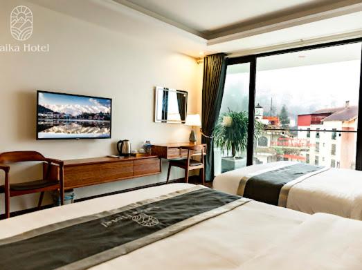 um quarto de hotel com duas camas e uma secretária e uma janela em Laika Hotel Sapa em Sapa