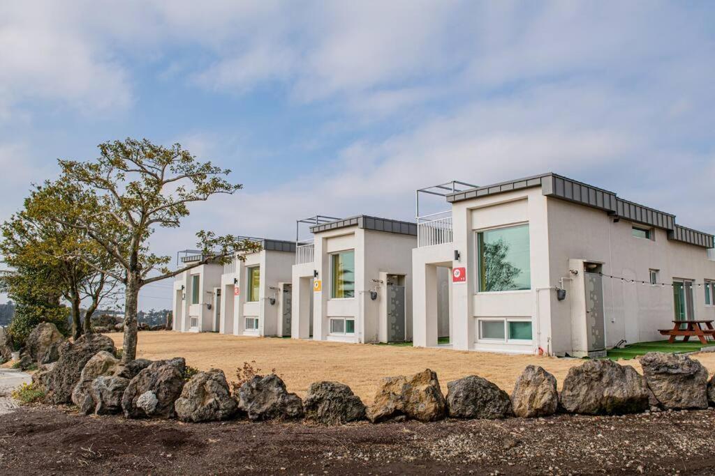 una fila de casas con rocas delante de ellos en Tamnaneun Farm en Jeju