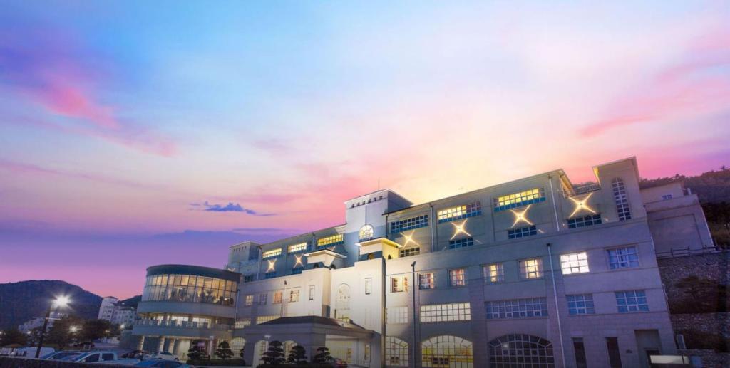 a large white building with a sunset in the background at Gyeongju Mauna Ocean Resort in Gyeongju