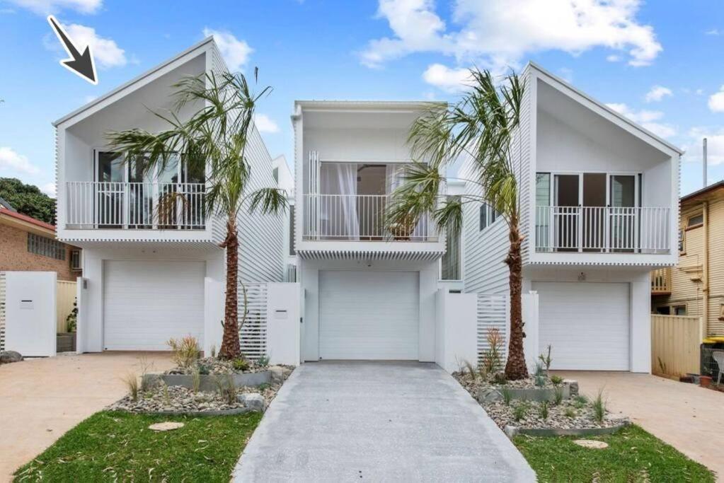 una casa blanca con palmeras delante en Noahs Beach House - at Flynns en Port Macquarie