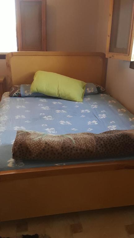 a bed with a yellow pillow and a blue comforter at بيت سيدون السياحي in Aswan