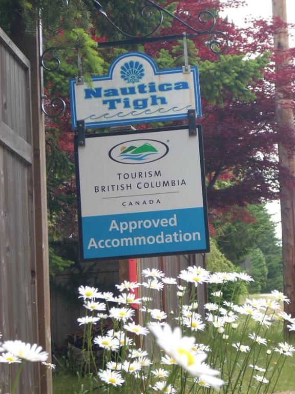 a sign for a garden with white flowers at At Nautica Tigh private keypad entrances in Qualicum Beach