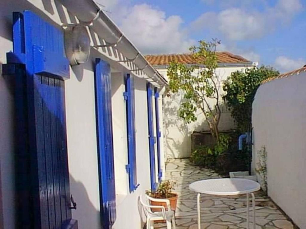 d'une petite terrasse avec une table et des portes bleues. dans l'établissement Maison simple à 200m des commerces, proche plage, 3 couchages - Noirmoutier-en-l'Île - FR-1-224B-620, à Noirmoutier-en-l'lle