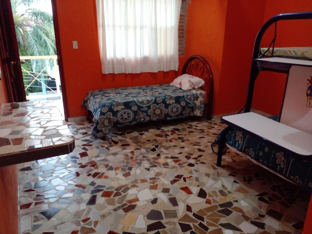 um quarto com paredes cor de laranja e um piso coberto por mosaicos em Quinta las golondrinas em Morelos