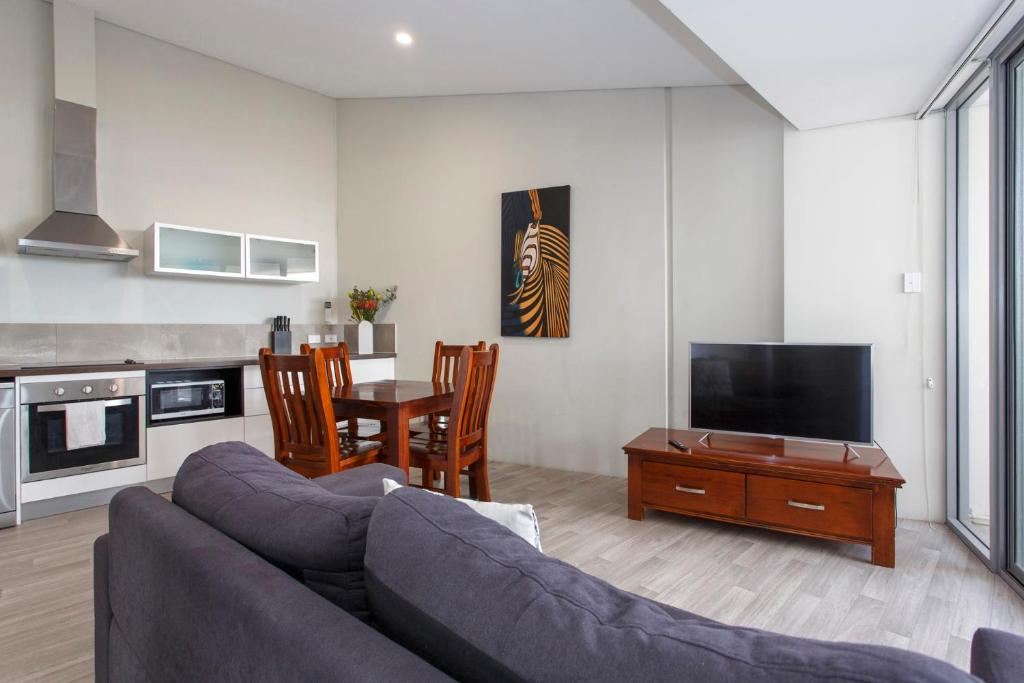 a living room with a couch and a tv and a table at Waverley apartment B-one bedroom wifi available in Perth