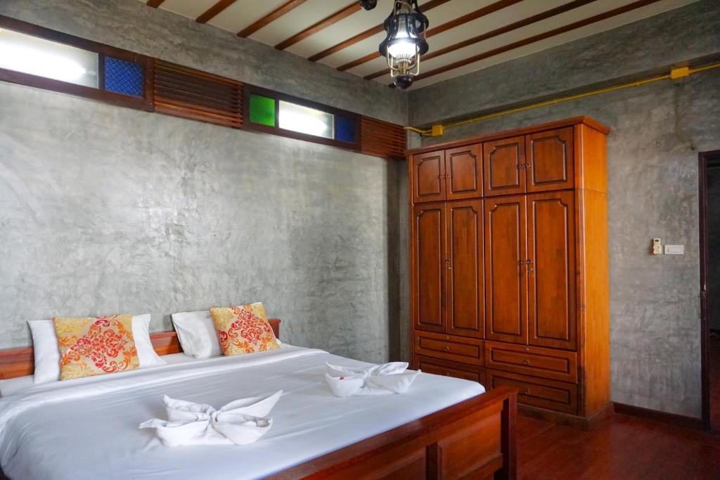 um quarto com uma grande cama branca e um armário de madeira em Tamnak Lanta @Chiang Mai em Chiang Mai