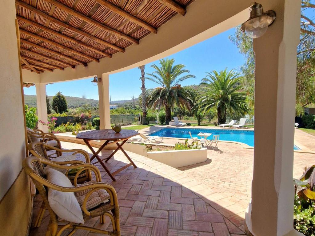 un patio con mesa, sillas y piscina en Casa da Aldeia en Bensafrim