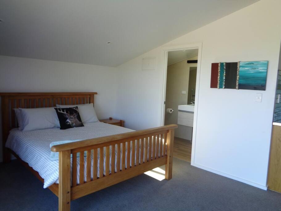 um quarto com uma cama de madeira e um banco de madeira em Ruby Bay Loft Apartment em Nelson