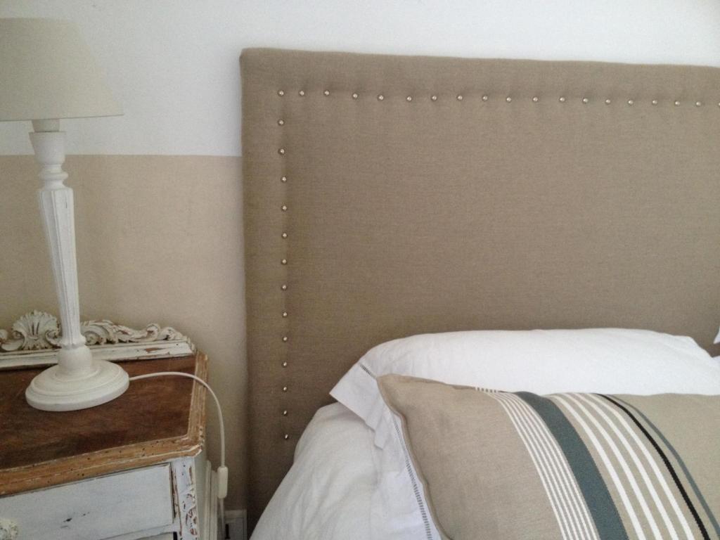 a bed with a headboard and a lamp on a table at Maison d'hôtes Urbegia in Ascain