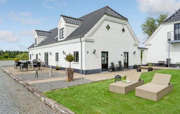 Casa blanca con mesa y sillas en el patio en Hedegaarden en Engesvang