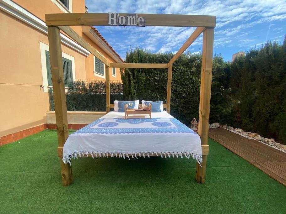 un letto con baldacchino in legno in un cortile di Can Guerrero situado a 500 metros de la playa! a Calas de Mallorca