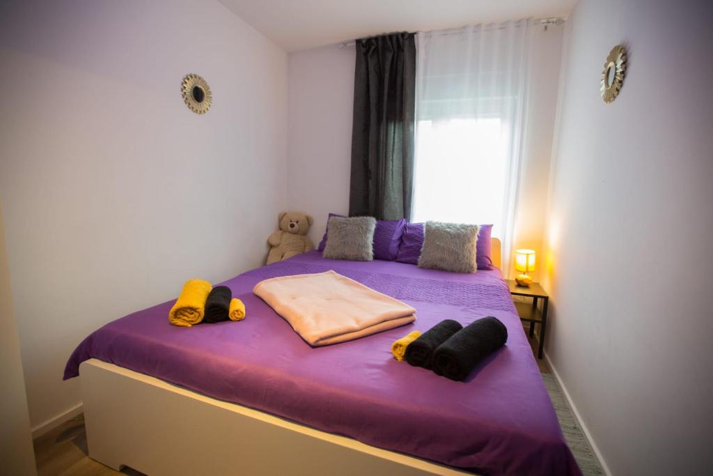 - une petite chambre avec un lit violet et une fenêtre dans l'établissement Apartmani Remete, à Zagreb
