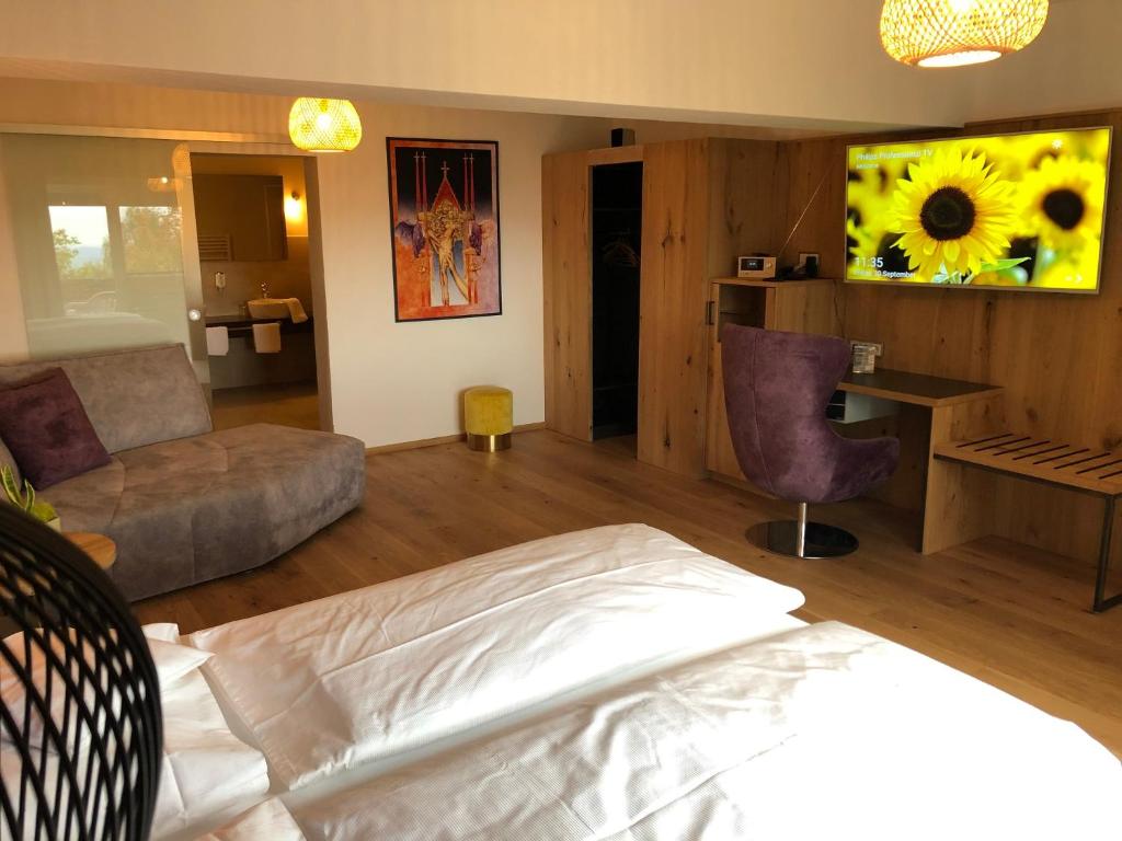 LallingにあるThula Wellnesshotel Bayerischer Waldのベッドルーム1室(ベッド1台付)、リビングルーム(ひまわり画付)