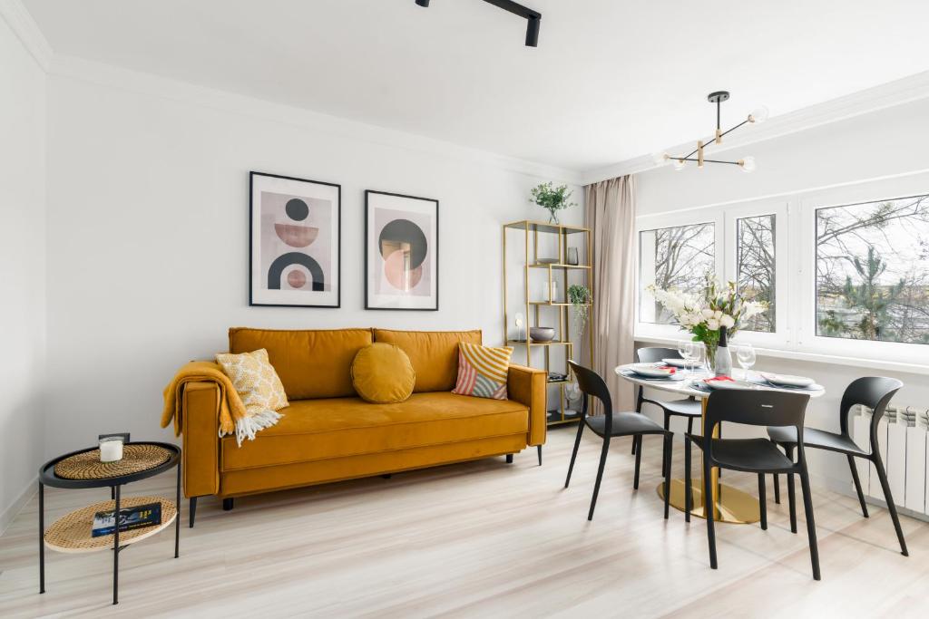 a living room with a yellow couch and a table at Grunwald Jesienna Apartment Comfort by Renters in Poznań