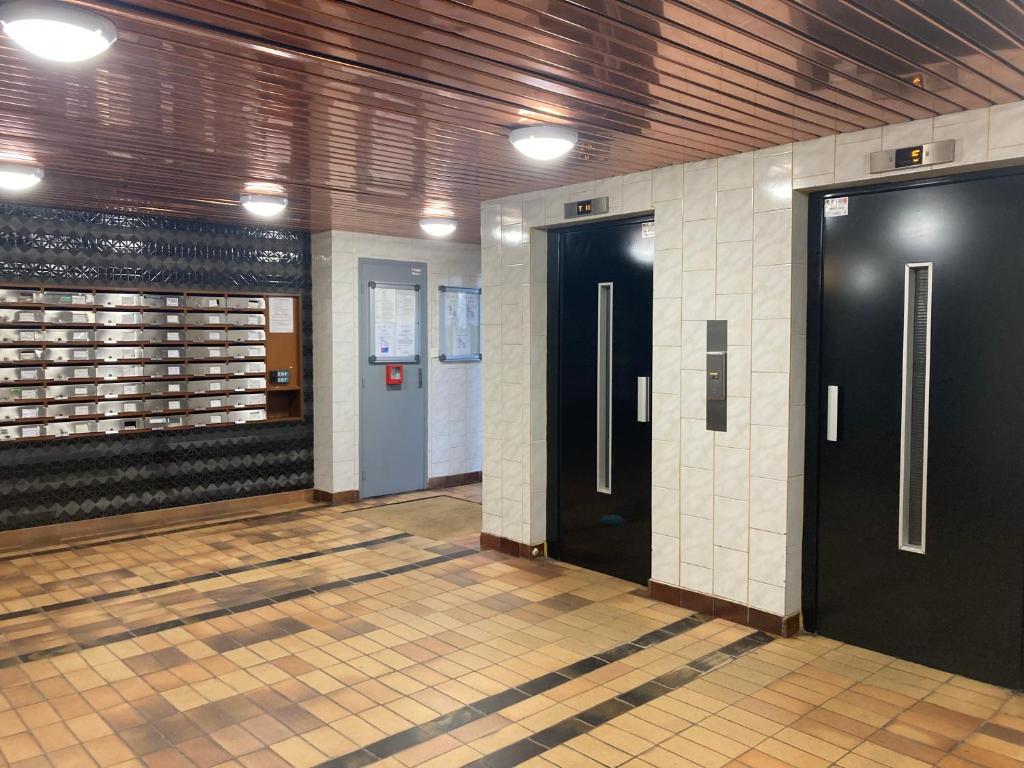 korytarz z dwoma czarnymi drzwiami i podłogą wyłożoną kafelkami w obiekcie Appartement familial 92m2 avec terrasse vue mer w mieście La Grande-Motte