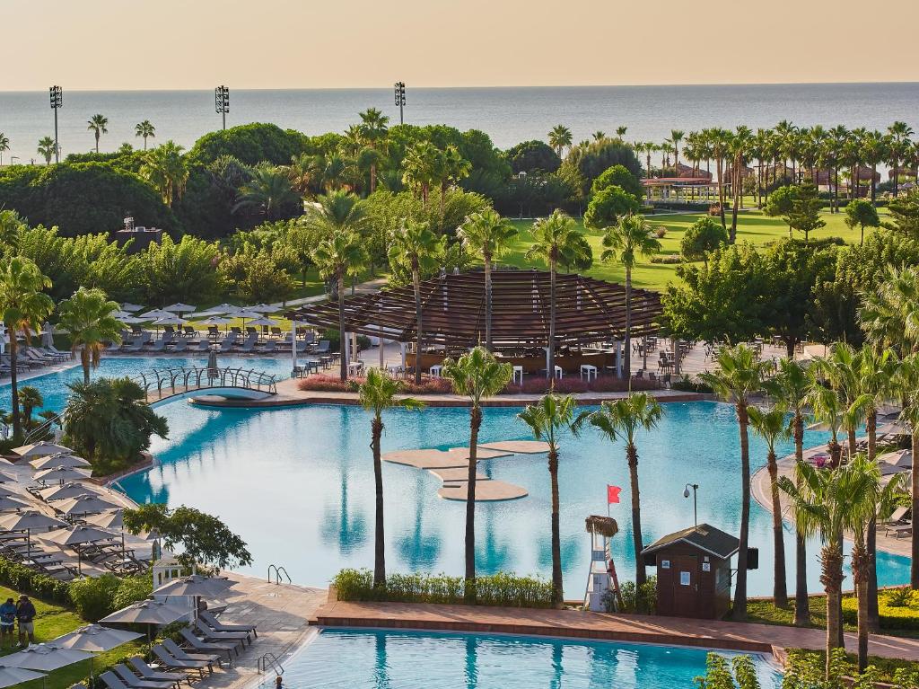 an aerial view of a resort pool with palm trees and the ocean at Lara Barut Collection-Ultra All Inclusive in Lara