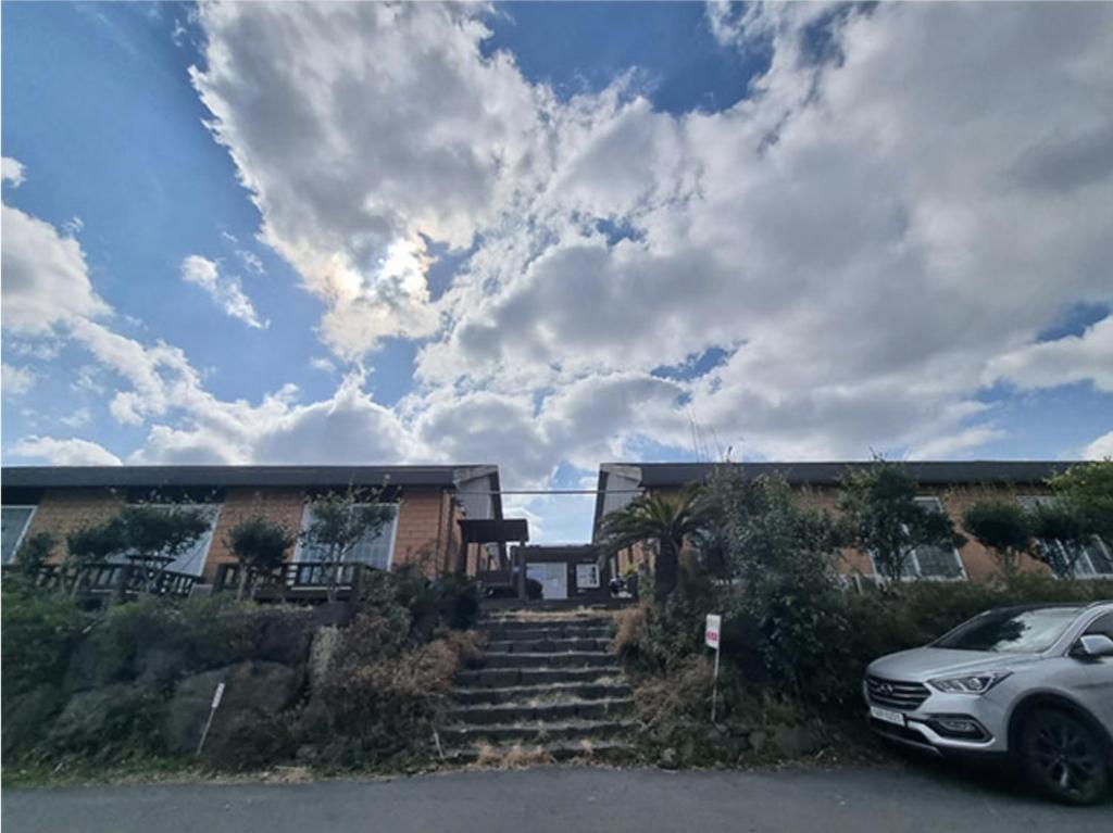 a car parked in front of a building with stairs at Joy Red Clay Resort in Jeju