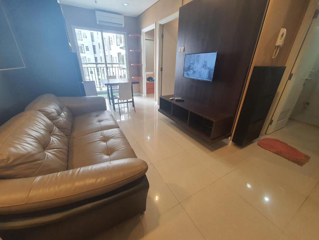 een woonkamer met een leren bank en een televisie bij Madison Park Apartment Near Mall Central Park in Jakarta