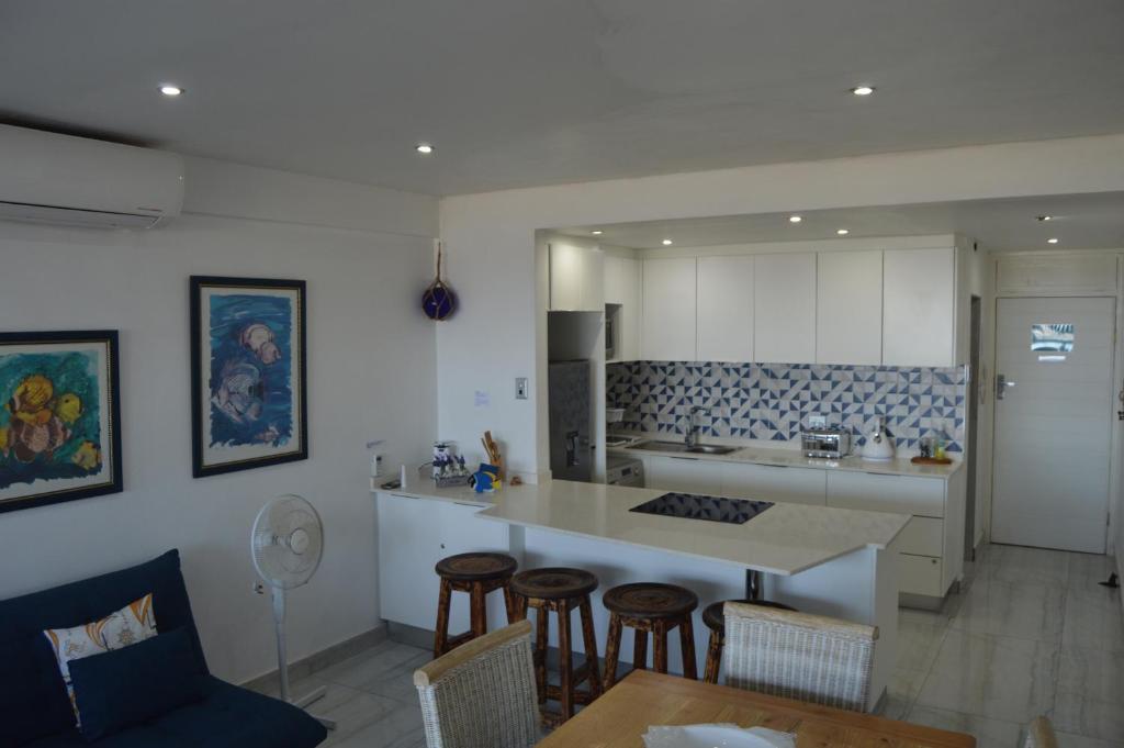 a kitchen with a counter and some chairs and a table at Accommodation Front - Luxurious 2 Sleeper Overlooking the Beachfront in Durban