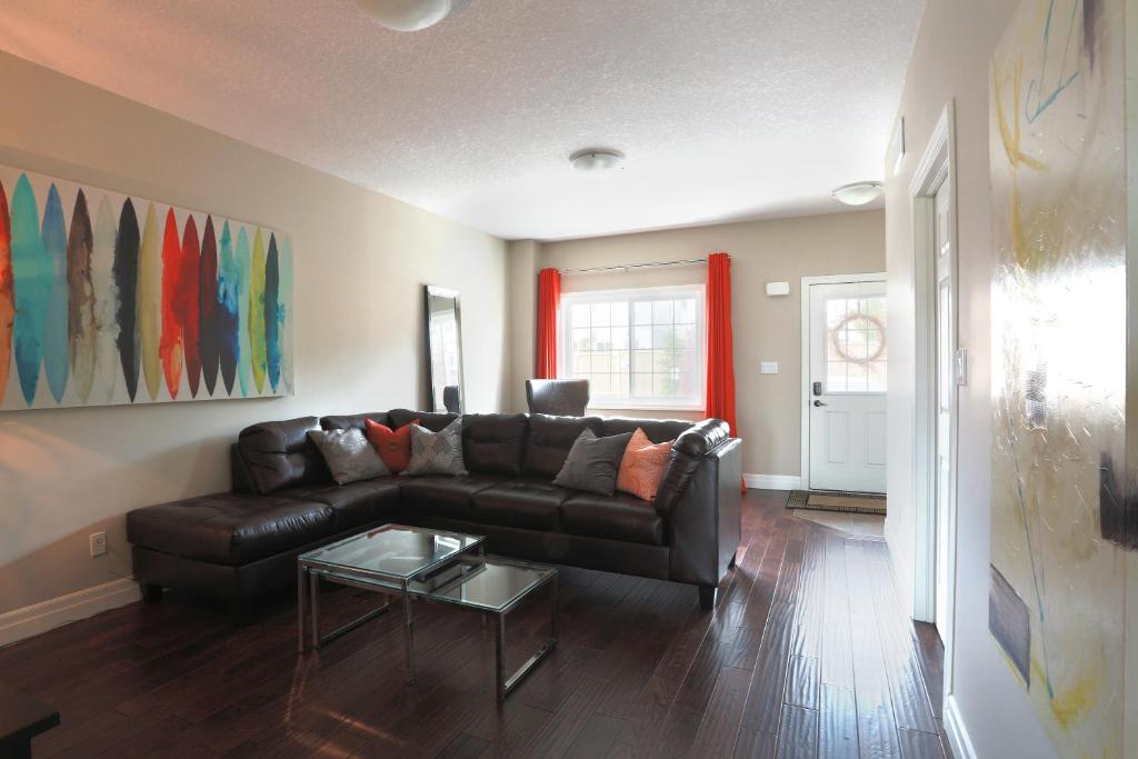sala de estar con sofá de cuero y mesa en Boardwalk Homes Executive Suites, en Kitchener
